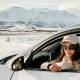Woman in car with snow and mountains in the background.